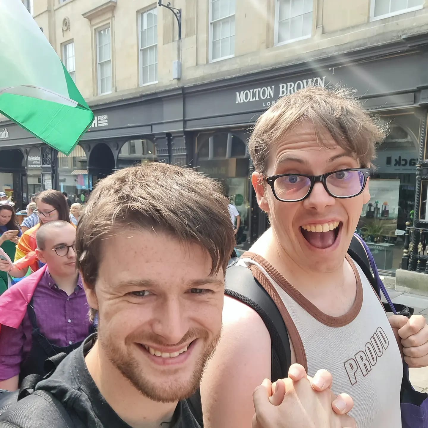 An image of two autistic queers walking hand-in-hand on a pride parade in Bath on 18th August 2024